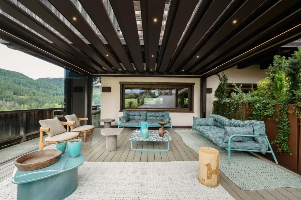 A premium Bioclimatic Roof Pergola featuring adjustable aluminium blades, casting a soft, controlled pattern of light and shadow over a landscaped garden space.
