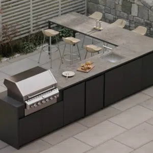 Premium outdoor kitchen featuring an integrated bar seating area, high-end cooking appliances, and a luxury workspace finish for a complete garden transformation.