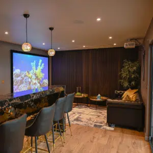Bespoke steel frame garden room configured into a premium home cinema room, featuring luxury tiered seating, immersive ambient lighting, and high-end audio-visual technology for a total garden transformation.
