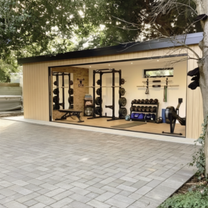 Bespoke steel frame garden room configured into a premium home gym, featuring heavy-duty fitness equipment and floor-to-ceiling glazing for a luxury garden transformation.