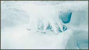 A clear close-up view of pristine, sparkling blue water inside a luxury hot tub, showcasing clean, functioning filtration jets against a high-end composite acrylic shell.