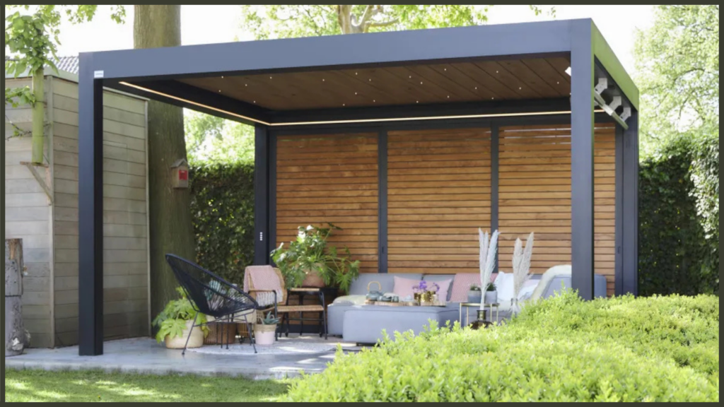 A stunning winter scenes showing a luxury black aluminium pergola fully enclosed with weatherproof side screens, illuminated by warm ambient LED lighting, with integrated infrared heaters warming a plush outdoor lounge area.