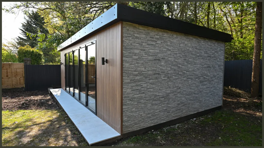 A contemporary timber-clad garden room building with large floor-to-ceiling glass sliding doors, integrated into a luxury landscaped backyard in Hadley Wood, Barnet.