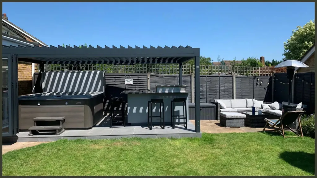 A luxury completed backyard project in Broxbourne, Hertfordshire, showcasing a premium built-in outdoor kitchen, a contemporary black aluminium louvred pergola, and a high-performance hydrotherapy hot tub.