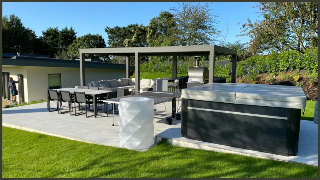 A luxury completed backyard project in Ware, Hertfordshire, showcasing a modern built-in outdoor kitchen, a bespoke aluminium louvred pergola, and a premium hydrotherapy hot tub.