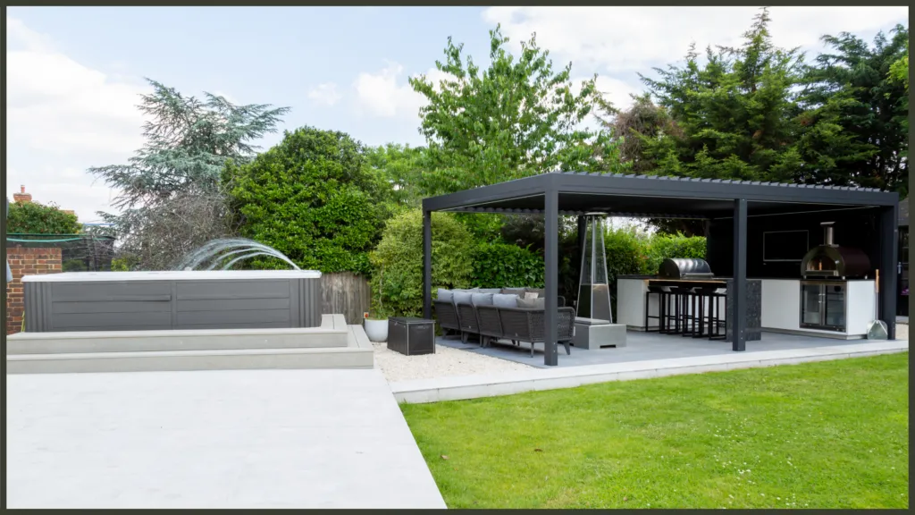 A luxury completed backyard project in Ilford, Redbridge, showcasing a premium built-in outdoor kitchen, a modern bespoke aluminium pergola, and an integrated Hydropool swim spa set within a landscaped garden.