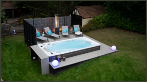 A luxury completed backyard project in Welwyn Garden City featuring a fully equipped modern outdoor kitchen, a sleek dark aluminium pergola, and an integrated Hydropool swim spa.